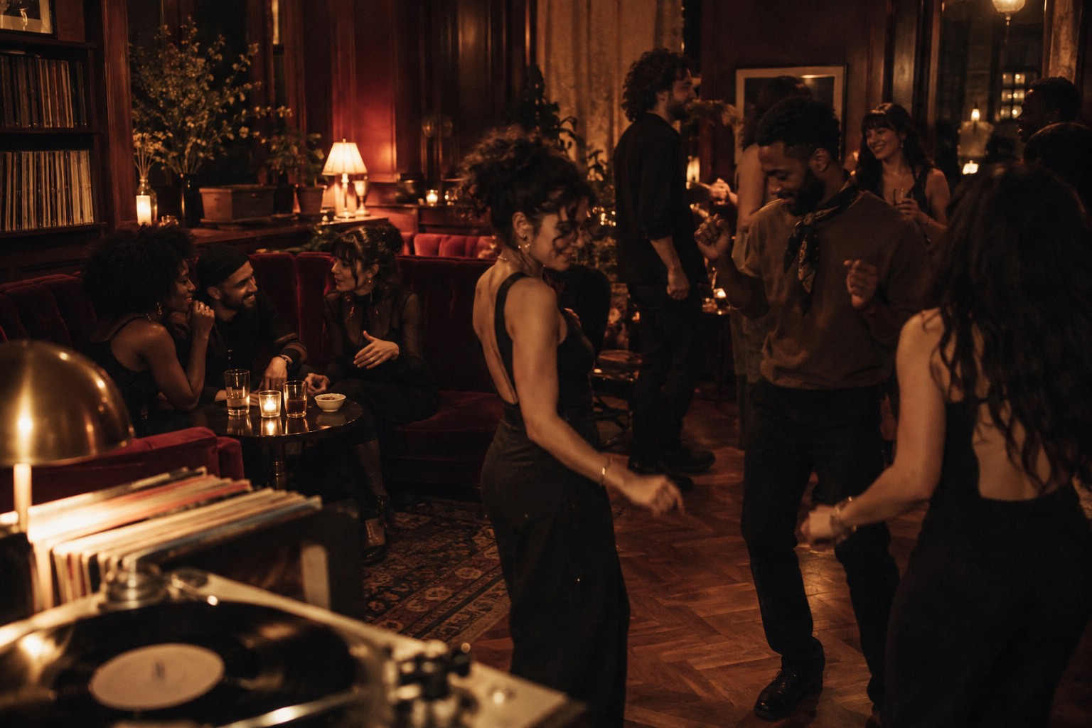 Friends sharing conversation and gentle movement in an intimate, warmly illuminated music salon